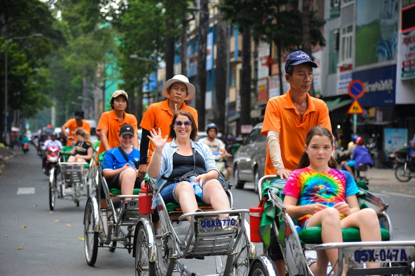 Les touristes étrangers apprécient l'expérience de cyclo-pousse à Ho Chi Minh-Ville. Photo: Saigon Adventure Tours