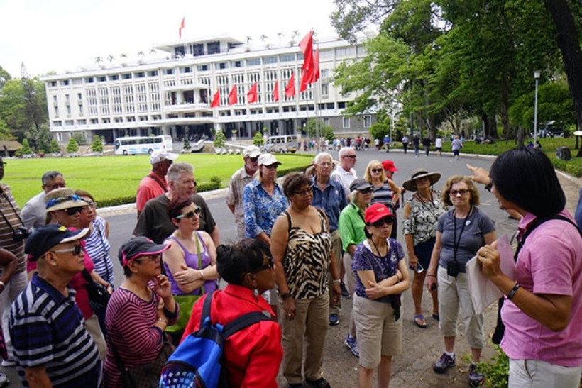 Des touristes étrangers écoutent une présentation sur l'histoire du Palais de l'Indépendance. Photo: doanhnhansaigon.vn