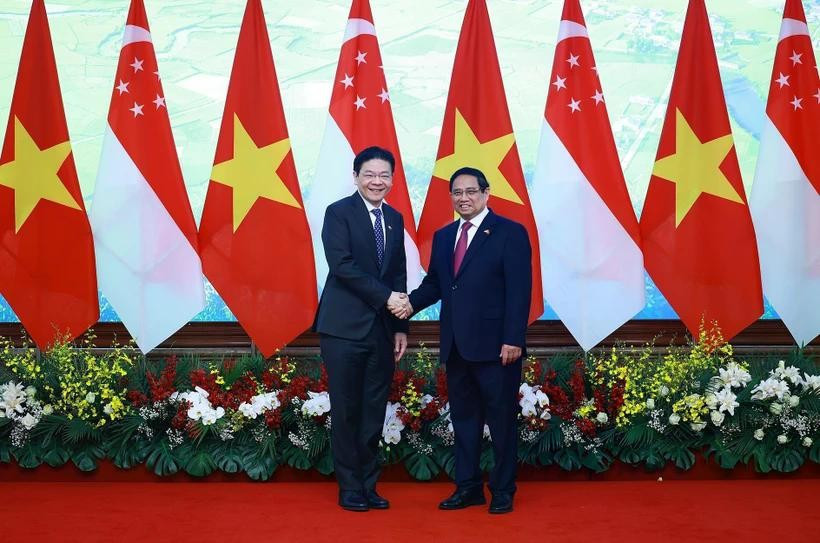 Le Premier ministre Pham Minh Chinh (à droite) et son homologue singapourien Lawrence Wong se serrent la main, à Hanoï, le 26 mars. Photo : VNA