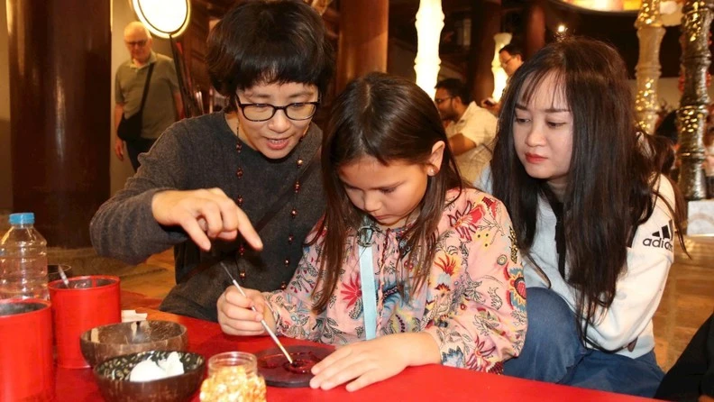 Des artistes et des visiteurs réalisent ensemble des œuvres en laque traditionnelle au Temple de la Littérature – Quôc Tu Giam. Photo : NDEL