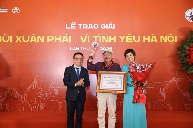 Lê Quôc Minh (à gauche), membre du Comité central du Parti, chef adjoint de la Commission de la sensibilisation, de l'éducation et de la mobilisation de masse du Comité central du Parti et président de l'Association des journalistes vietnamiens, et Vu Viêt Trang (à droite), directrice générale de l'Agence vietnamienne d’information, remettent le Grand prix au musicien Trân Tiên. Photo : VNA
