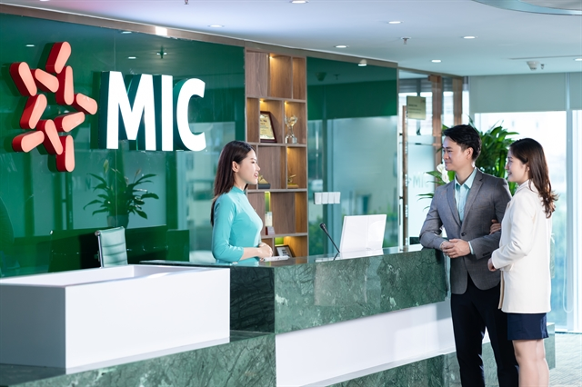 Une employée de la Military Insurance Company (MIC) discute avec des clients dans ses bureaux. Photo : mic.vn