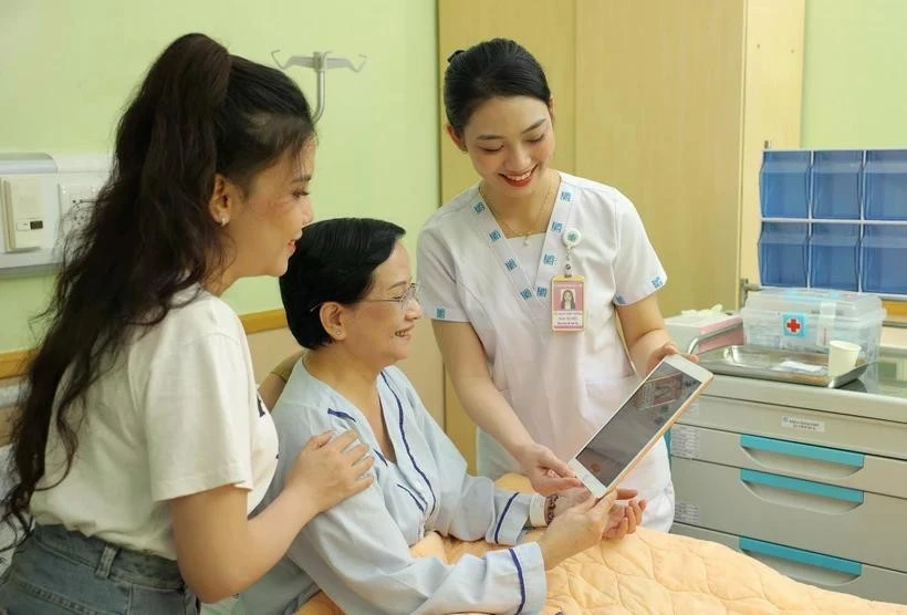 Le personnel médical de l'hôpital de l'Université de médecine et de pharmacie d'Ho Chi Minh-Ville utilise des tablettes pour mettre à jour et partager des informations avec une patiente. Photo : VNA