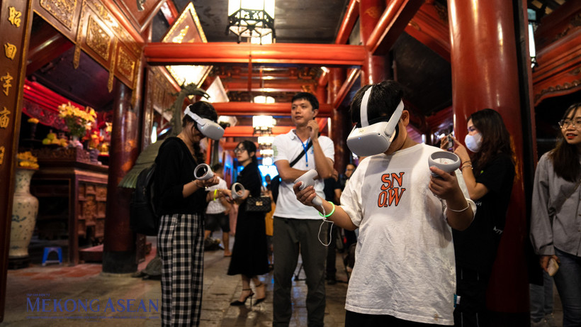 Les touristes découvrent l'écriture calligraphique grâce à la technologie de réalité virtuelle au Temple de la Littérature. Photo : mekongasean.vn