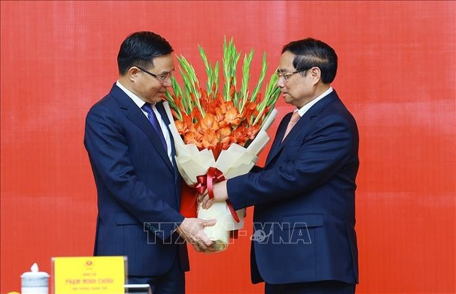 Le Premier ministre Pham Minh Chinh (à droite) félicite Lê Manh Hung pour sa nomination au poste de ministre par intérim de l’Industrie et du Commerce. Photo : VNA