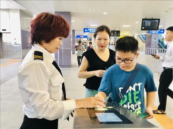 Une employée de Hanoi Metro guide un jeune usager du métro de Hanoi. Photo : VNA
