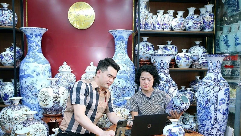 L’artisan Trân Trung Hiêu, dans la commune de Bat Tràng, district de Gia Lâm, à Hanoi, partage avec sa collègue sur la manière d’introduire des céramiques sur les plateformes de commerce électronique. Photo : NDEL