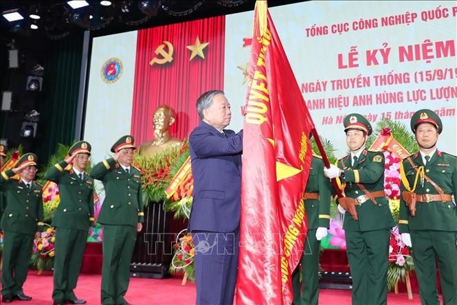 Le secrétaire général du Parti Tô Lâm épingle l’insigne de Héros des Forces armées populaires sur le drapeau traditionnel du Département général de l’industrie de la défense. Photo : VNA