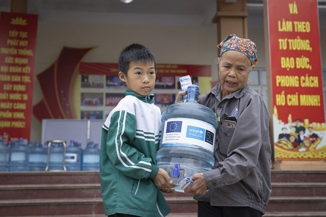 Dans la province de Thai Nguyên, dévastée par le typhon, une femme et son petit-enfant rapportent chez eux une bouteille d'eau potable fournie grâce au soutien de l'UE et de l'UNICEF. Photo : UNICEF Vietnam