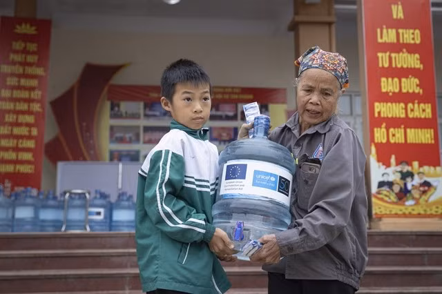Dans la province de Thai Nguyên, dévastée par le typhon, une femme et son petit-enfant rapportent chez eux une bouteille d'eau potable fournie grâce au soutien de l'UE et de l'UNICEF. Photo : UNICEF Vietnam