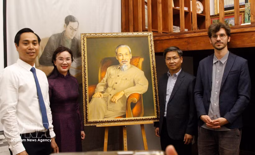 La directrice du site des vestiges du président Hô Chi Minh dans la zone du Palais présidentiel, Lê Thi Phuong, le directeur du Musée de l’Histoire vivante, Thomas Le Goff (premier rang, à droite) et d’autres membres de la délégation posent avec un grand portrait du Président Hô Chi Minh. Photo : VNA
