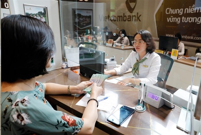 Une cliente effectue un dépôt dans un guichet bancaire à Hanoi. Photo : VNA