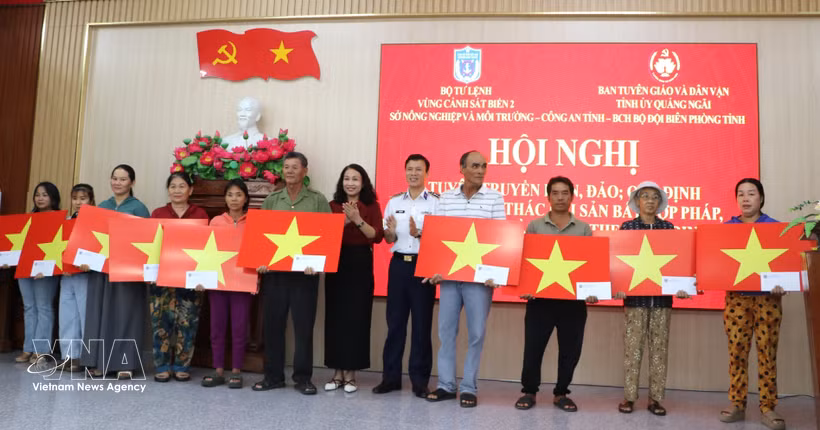 Des représentants du commandement de la 2e région des garde-côtes et du Comité de l'information, de l'éducation et de la mobilisation des masses du Comité provincial du Parti de Quang Ngai offrent des cadeaux et des drapeaux nationaux aux pêcheurs. Photo : VNA