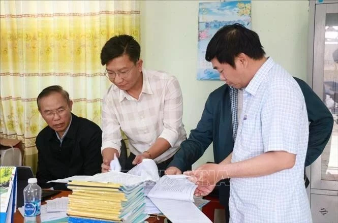 Le vice-ministre de l'Agriculture et du Développement rural, Phung Duc Tiên (premier à gauche), et les inspecteurs examinent les registres quotidiens des bateaux de pêche au port de pêche de Dông Tac, dans la ville de Tuy Hoa, province de Phu Yên. Photo : VNA