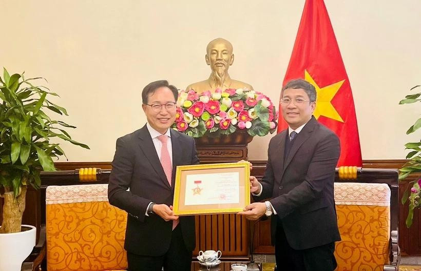 Le vice-ministre permanent des Affaires étrangères Nguyên Minh Vu (à droite) remet l’insigne «Pour la cause des affaires étrangères du Vietnam» au directeur général de Samsung Vietnam, Choi Joo Ho, à Hanoi, le 13 février. Photo : VNA