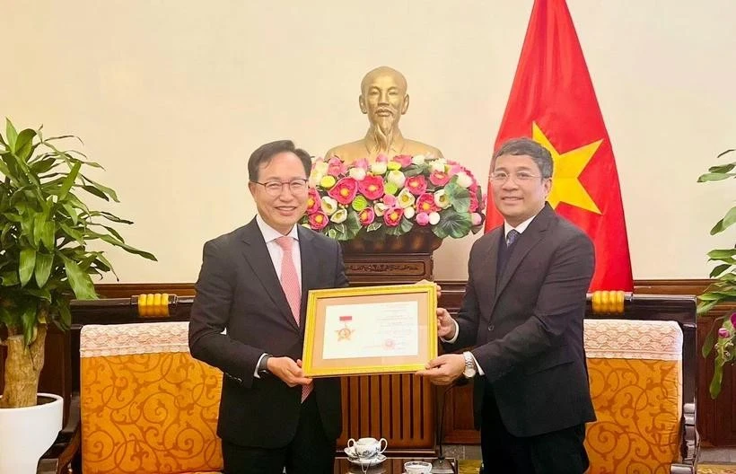 Le vice-ministre permanent des Affaires étrangères Nguyên Minh Vu (à droite) remet l’insigne «Pour la cause des affaires étrangères du Vietnam» au directeur général de Samsung Vietnam, Choi Joo Ho, à Hanoi, le 13 février. Photo : VNA