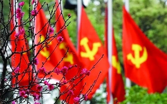 Des drapeaux frappés de la faucille et du marteau au milieu des fleurs de pêcher. Photo: VNA