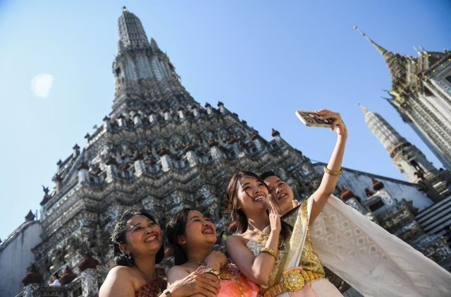 Un groupe de touristes vietnamiens en costumes traditionnels thaïlandais prennent des photos devant le temple Wat Arun, à Bangkok, en Thaïlande. Photo : Reuters