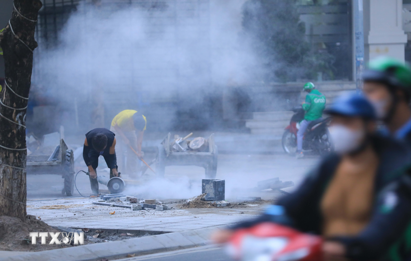 Des tailleurs de pierre lors de la construction d’un trottoir dans un quartier de Hanoi. Photo : VNA