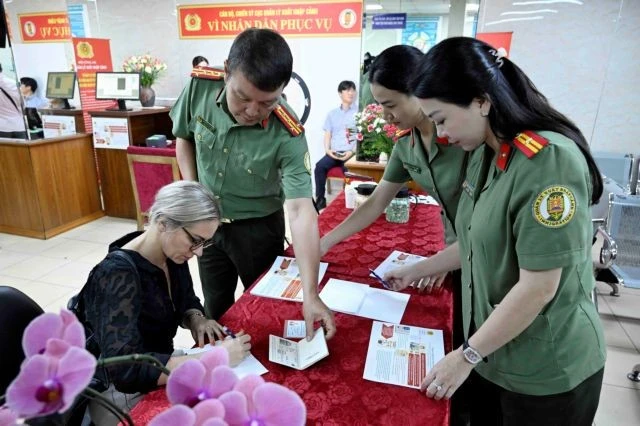 Des agents du Département de l’immigration aident une ressortissante étrangère à Hanoi à remplir les formulaires pour les comptes d’identification électronique de niveau 2 avec VneID, le 1er juillet. Photo : VNA