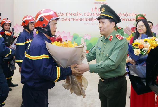 Les secouristes accueillis à Hanoi avec des fleurs. Photo : VNA