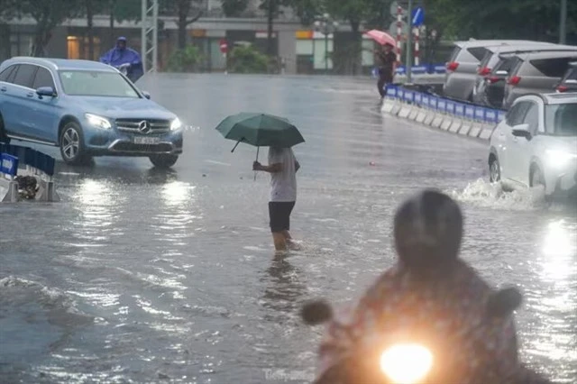 La rue Kim Ma inondée après de fortes pluies avec des voitures et des personnes traversant l'eau profonde. Photo: tienphong.vn