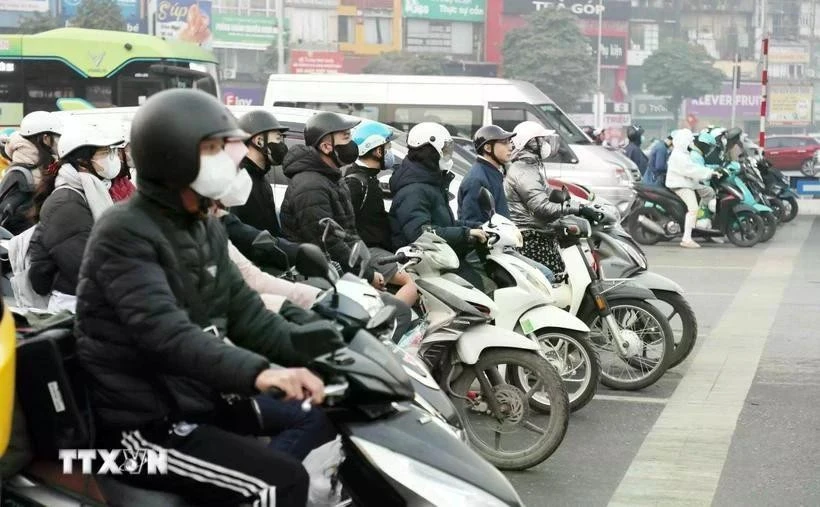 Les gens s’arrêtent au feu rouge dans une rue.Photo : VNA