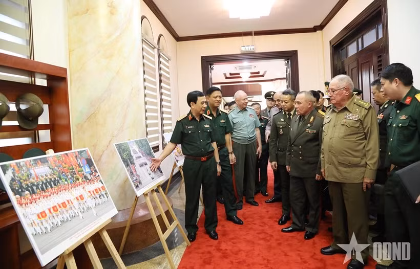 Le général Phan Van Giang présente aux dirigeants militaires étrangers une exposition de photos présentant les activités commémorant le 80e anniversaire de la Révolution d’Août et de la Fête nationale, le 2 septembre. Photo : qdnd