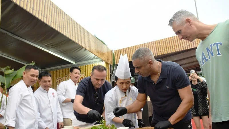 Des touristes internationaux découvrent la préparation de salades de poisson au Festival gastronomique de Dà Nang 2025. Photo: NDEL