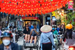Des touristes internationaux profitent de promenades en cyclo-pousse dans le vieux quartier de Hanoï. Photo znews.vn