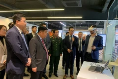 Le vice-Premier ministre Nguyen Chi Dung et les délégués écoutent la présentation du Centre de recherche-développement (R&D) et du Centre d’Excellence consacrés à l’intelligence artificielle et au jumeau numérique. Photo : Quan doi nhan dan