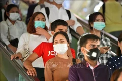 À Bangkok, en Thaïlande, des personnes portent un masque pour prévenir la COVID-19. (Photo : XINHUA/VNA)