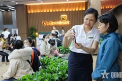 Des employés de la Banque commerciale par actions pour le commerce extérieur du Vietnam (Vietcombank) guident des clients dans la réalisation de l’authentification biométrique. Photo : Quân đội nhân dân