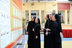 Des religieuses de la Congrégation des Amantes de la Sainte-Croix, au 31 rue Nhà Chung, consultent la liste des candidats au bureau de vote n°1, dans le quartier de Hoàn Kiem. Photo : VNA