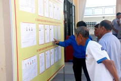 Des électeurs issus des minorités ethniques de la commune de Bắc Bình (Lâm Dông) consultent les biographies des candidats avant le jour du scrutin. Photo : VNA