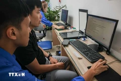 Les bénévoles de l'Union des jeunes guident les gens pour déclarer en ligne et faire des certificats de naissance pour leurs enfants au point de service administratif public du quartier de Cua Nam. Photo : VNA
