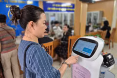 Les gens font l'expérience de robots IA appliquant la technologie de l'intelligence artificielle pour soutenir les procédures administratives dans le quartier de Cua Nam, dans la ville de Hanoi. Photo : VNA