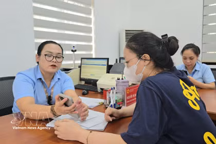 Des fonctionnaires du quartier de Mao Khe guident une citoyenne dans le dépôt en ligne de ses dossiers de certification sur le Portail national de la fonction publique. Photo : TTXVN
