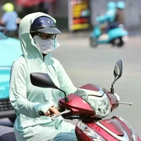 Une motocycliste se couvre le visage d’un tissu pour s’abriter de la chaleur. Photo : VNA