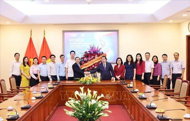 Le vice-président de la Commission de la sensibilisation, de l’éducation et de la mobilisation des masses du Comité central du Parti, Lai Xuân Môn (à gauche, au centre), offre des fleurs en guise de félicitations à la VNA. Photo : VNA lai-xuan-mon-vna.jpg
