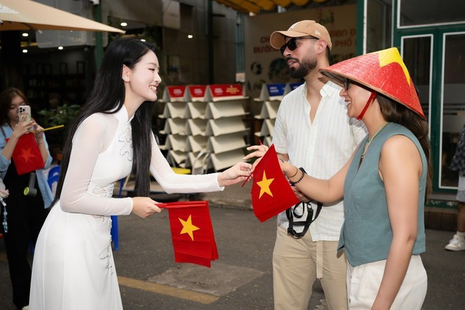 Deux touristes internationaux reçoivent des drapeaux nationaux dans la rue du livre de Hô Chi Minh-Ville. Photo : VietnamPlus touristes-internationaux.jpg