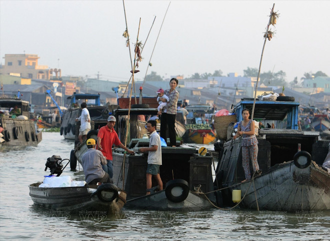 À la proue de chaque bateau, des perches en bambou arborent des échantillons des produits vendus, permettant aux clients d’identifier rapidement ce qu’ils recherchent. Photo : VNP marche-flottant.jpg