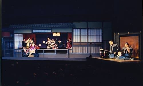Depuis une plate-forme surélevée (yuka), le narrateur (tayu) raconte l’histoire tandis qu’un musicien joue du shamisen, un luth à trois cordes. Le tayu interprète tous les personnages, hommes et femmes, adaptant sa voix et ses intonations aux rôles et aux situations. Si le tayu « lit » un texte écrit, il jouit d’une grande liberté d’improvisation. Photo: UNESCO bunraku.jpg