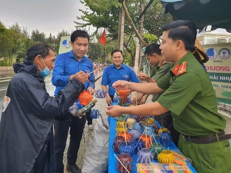 Des gens apportent des bouteilles en plastique usagées, des canettes et de vieilles piles pour les échanger contre des lanternes de la fête de la mi-automne dans le cadre d'un programme appelant les gens à trier les déchets plastiques, contribuant ainsi à la construction d'une Bên Tre verte. Photo : VNA