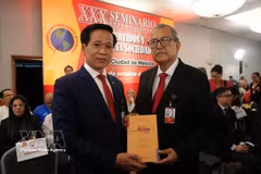Hoang Phuc Lam, professeur associé et docteur, directeur adjoint de l’Académie nationale de politique Ho Chi Minh remet le livre à un membre du Parti du Travail du Mexique. Photo : VNA