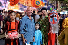 Des touristes internationaux s'imprègnent de l'ambiance de la Fête de la mi-automne au bord du lac Hoan Kiem, entourés de jouets traditionnels colorés. Photo : VNA