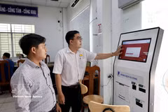 Des agents du Centre de services administratifs publics du quartier de Long Xuyen (province d'An Giang) guident des gens dans leurs démarches en ligne sur le portail national des services publics. Photo : VNA