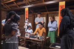 Des touristes assistent à une démonstration de calligraphie lors d'une visite nocturne du Temple de la Littérature à Hanoï. Photo : VNA