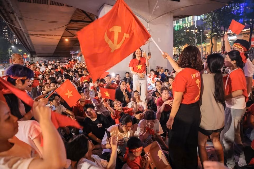 Les gens, avec les drapeaux rouges, attendent ensemble le défilé militaire et populaire célébrant le 80e anniversaire de la Fête nationale. Photo : Khanh Hoa/VNA