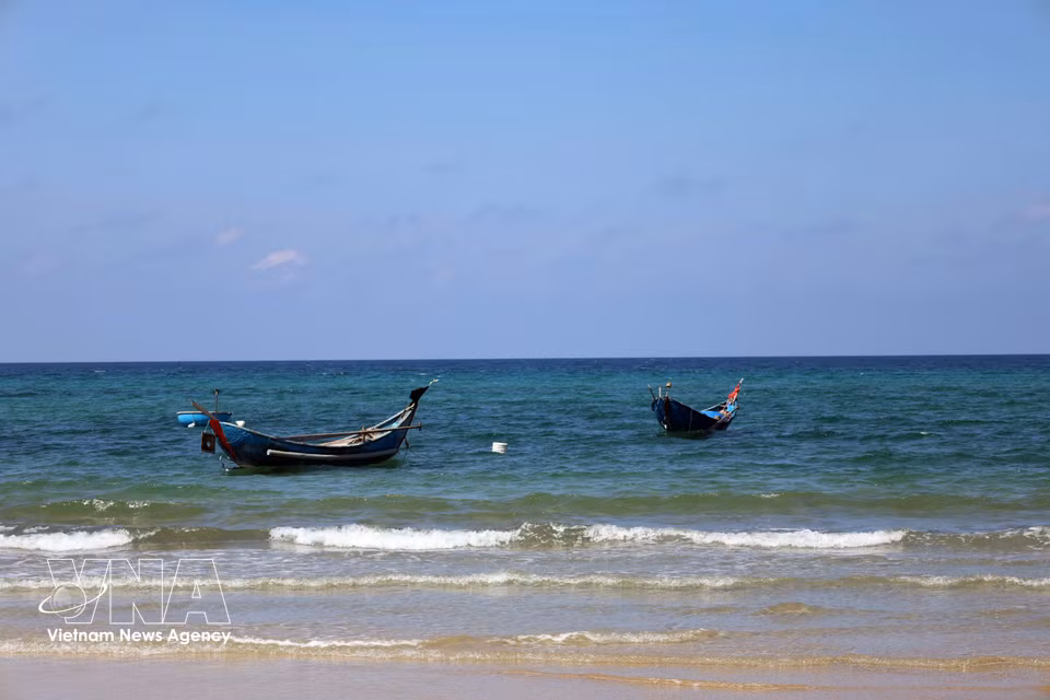 De petites embarcations de pêche des habitants sont amarrées sur les eaux d’un bleu limpide.